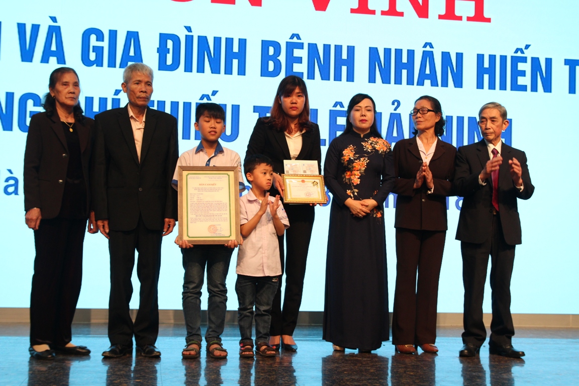 Bộ trưởng Bộ Y tế Nguyễn Thị Kim Tiến trao kỷ niệm chương và chụp ảnh cùng gia đình Thiếu tá Lê Hải Ninh. (Ảnh: PV/Vietnam+)