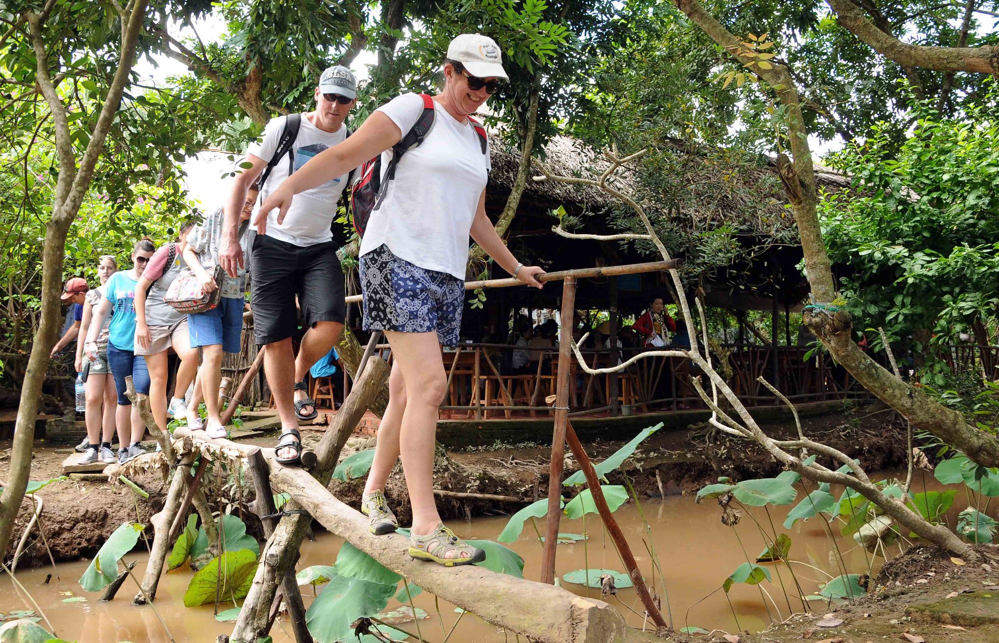 Du khách nước ngoài thích thú đi cầu khỉ ở miệt vườn miền Tây. (Nguồn ảnh: TTXVN)